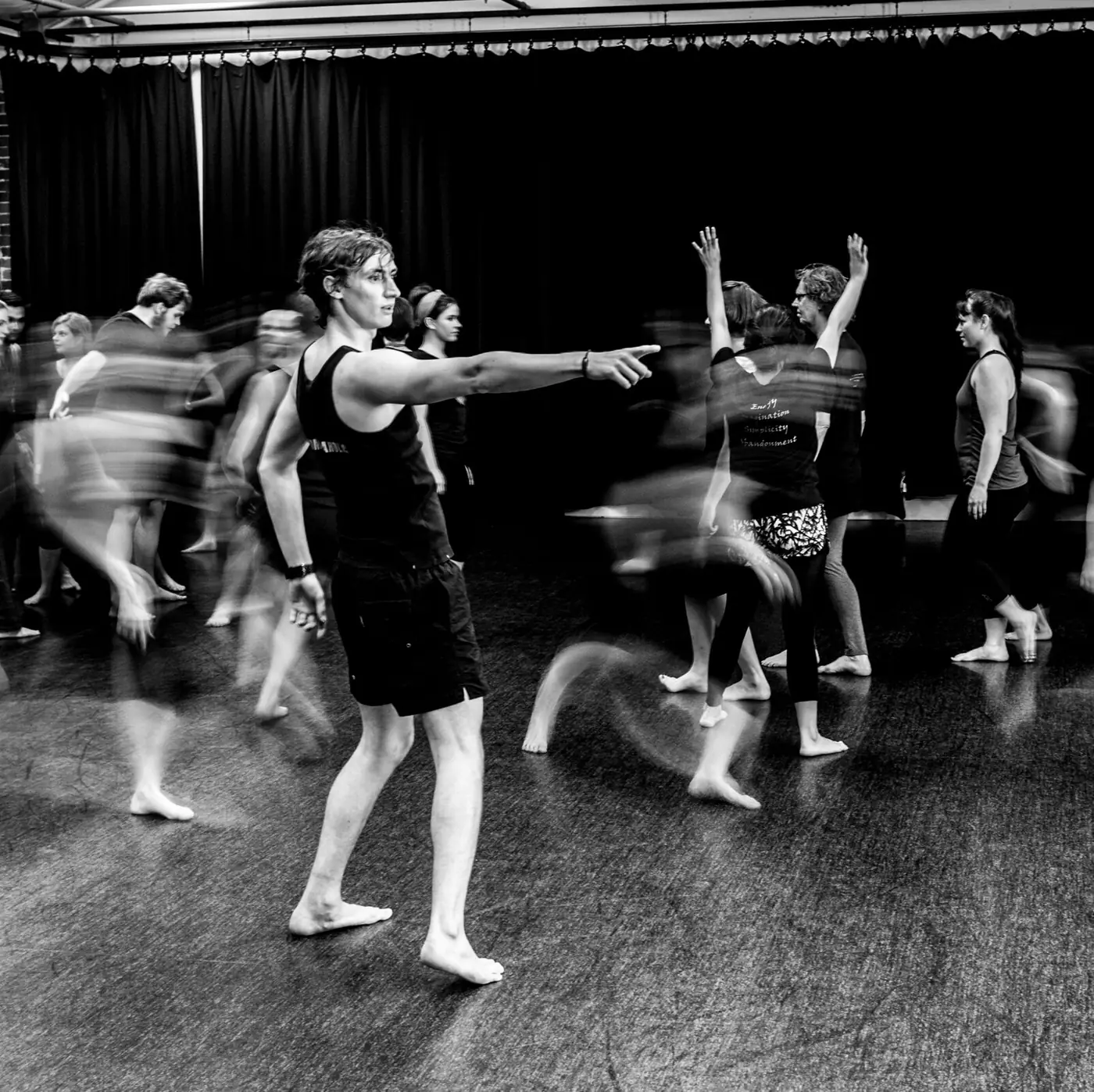 A workshop group moving through a studio, one participant pointing ahead while others blur in motion